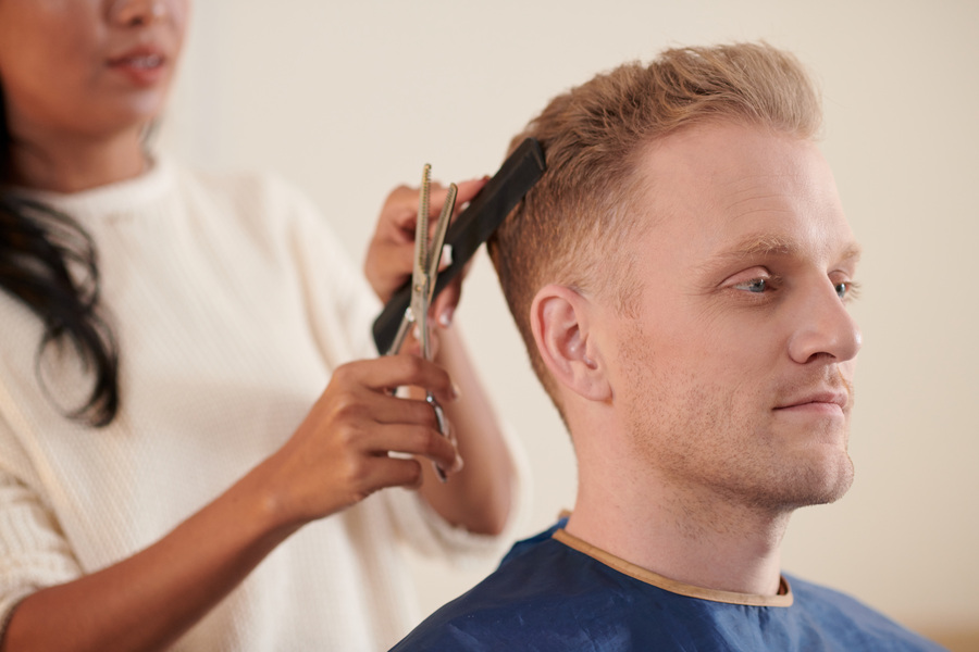 Une coiffeuse entrain de faire un taper au cheveu de son client, lequel l'en a demandé