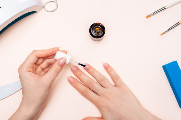 Une personne qui applique du nail prep sur ses ongles avant de mettre de primer