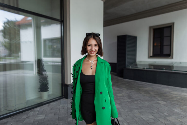 Une femme qui porte une robe noire avec un blazer vert