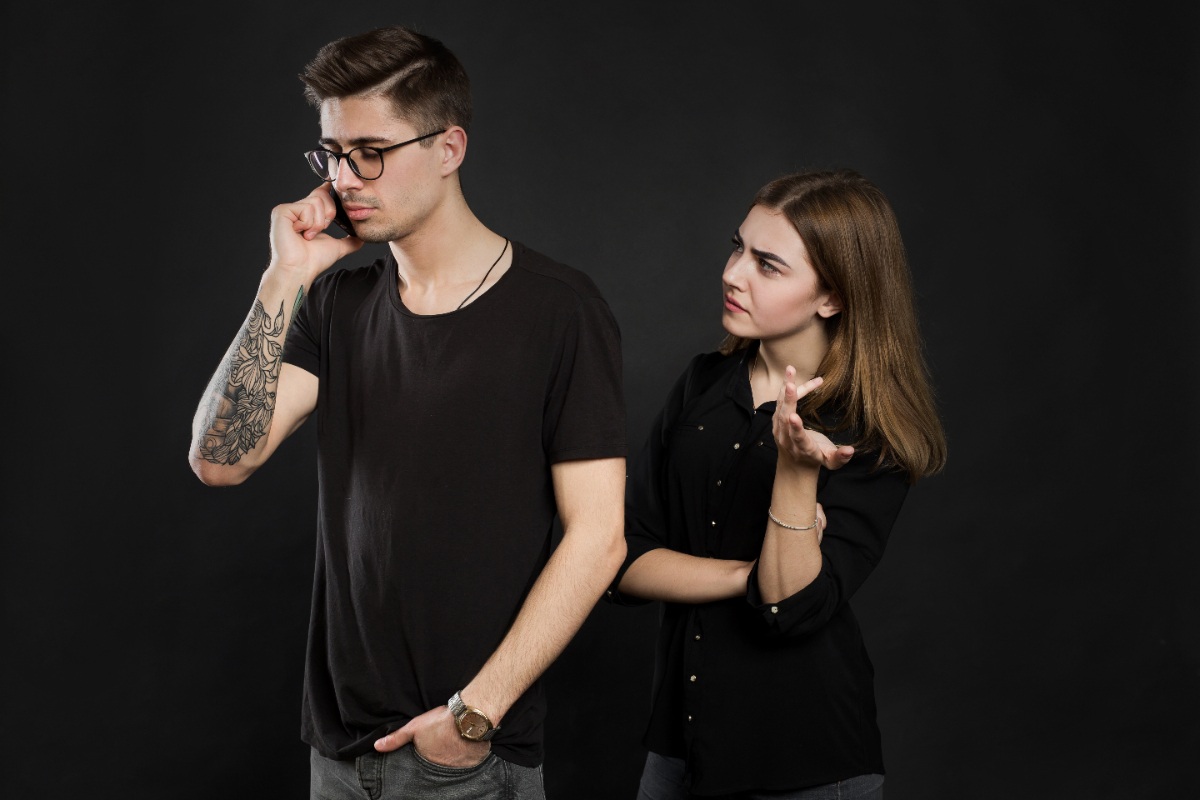 Une femme frustrée derrière son homme au téléphone