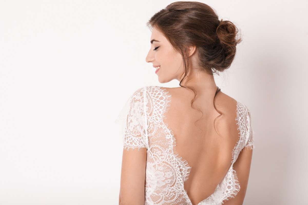 Une belle femme qui enfile une robe de mariée dos nu