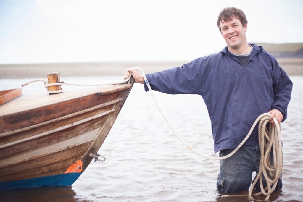 Un homme tenant une corde appuyée sur un bateau à rames