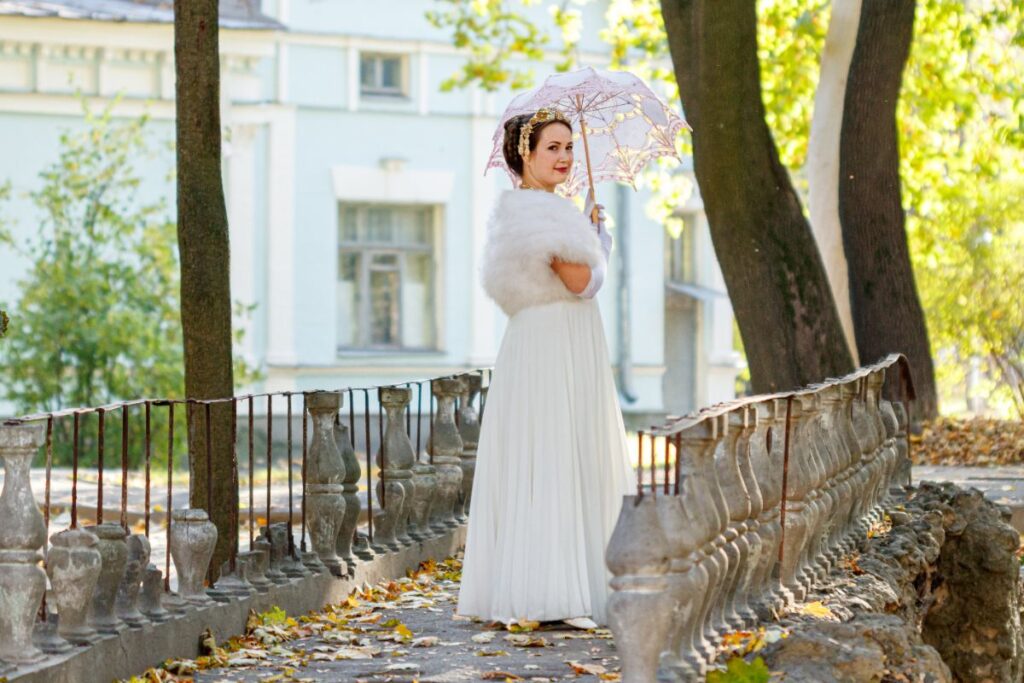 Une jeune mariée habilée avec une robe blanche et tient une parapluie