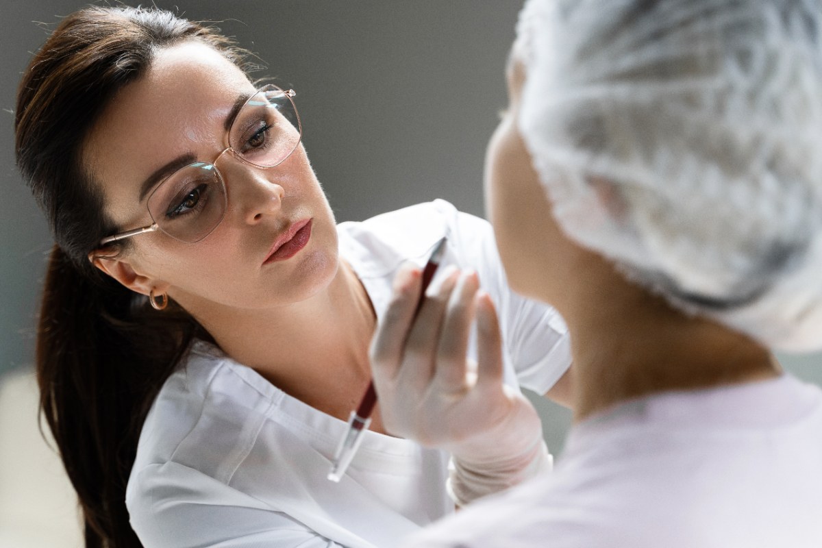 Un médecin esthétique qui applique un traitement facial surle visage d'une patiente