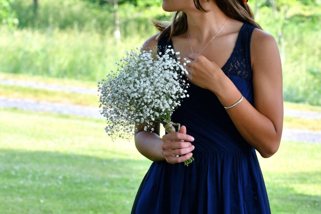 Une mariée dans une robe bleu marine, qui tient un bouquet de fleur blanc