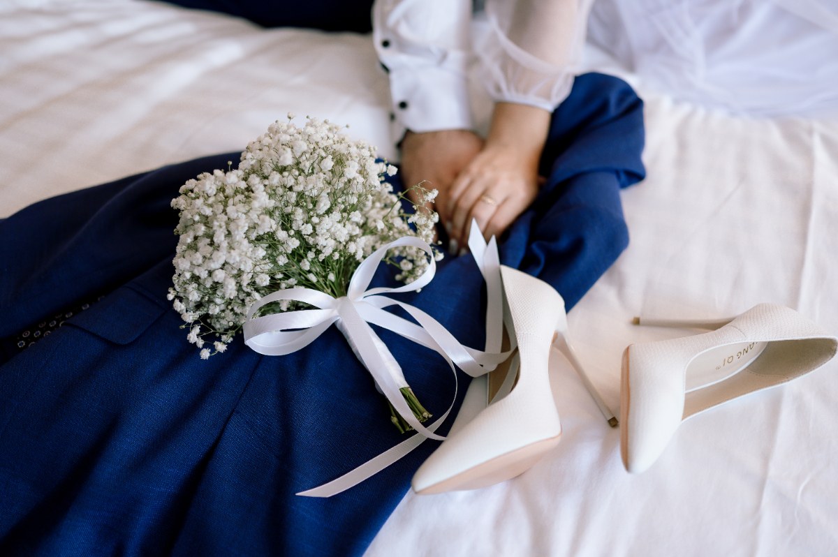 Une personne qui prépare une robe de mariée bleu marine avec un talon et un bouquet de fleur