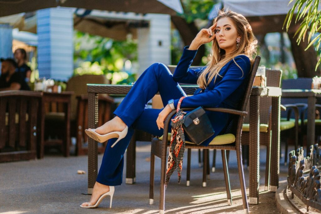 Une femme assise sur une chaise en portant un tailleur bleu marine et un talon blanc