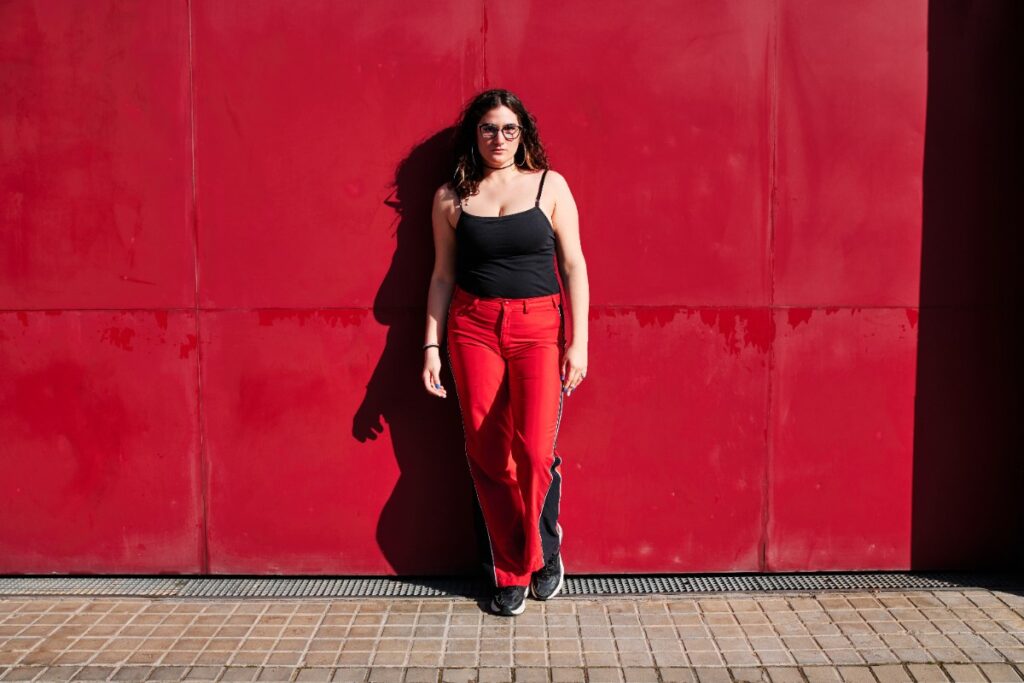 Une femme qui porte un haut noir et un pantalon rouge