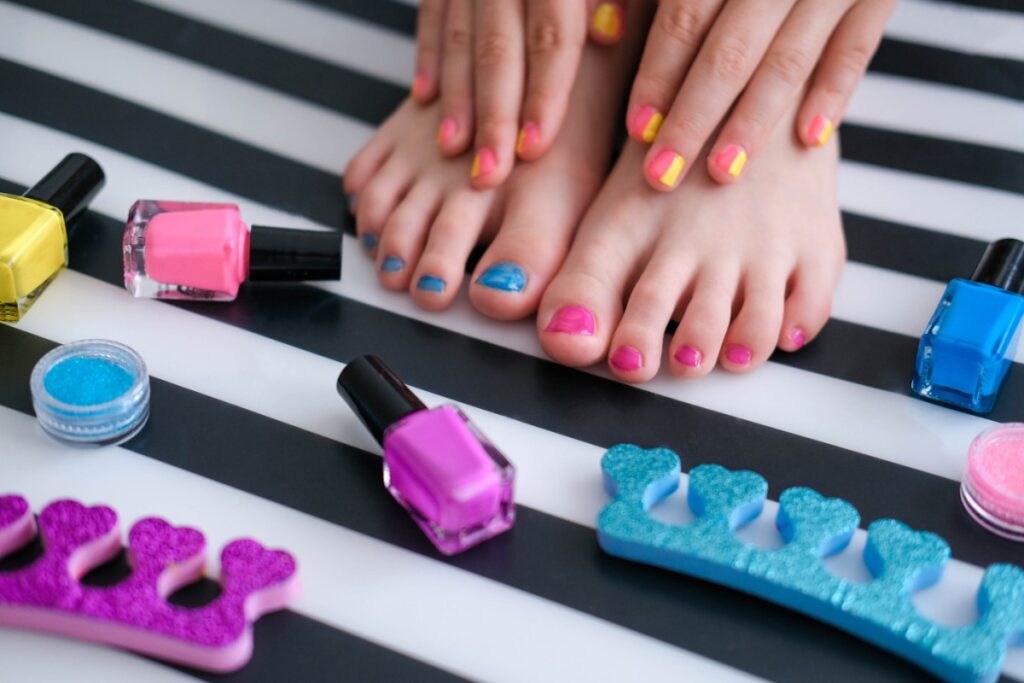 Mains et pieds manucurés avec des vernis par terre