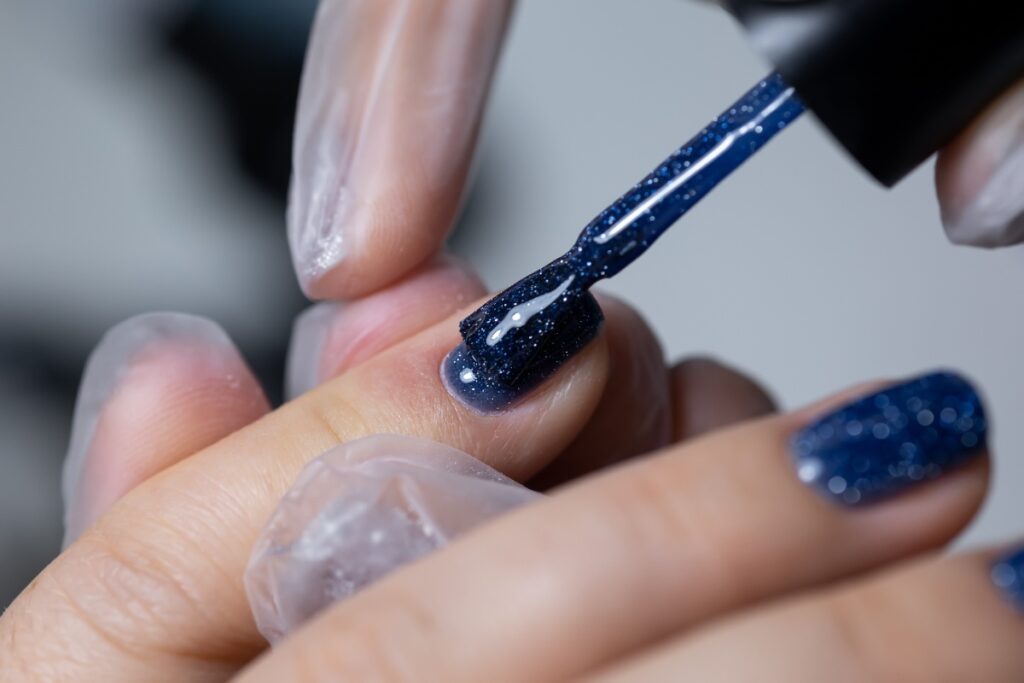 Une personne qui applique du vernis à ongle bleu