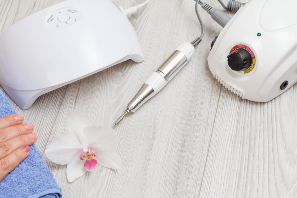 Une ponceuse à ongle professionnelle et une lampe UV sur la table