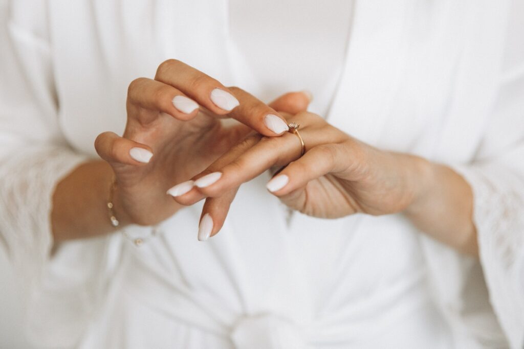Des jolies mains avec des bagues et des ongles blancs