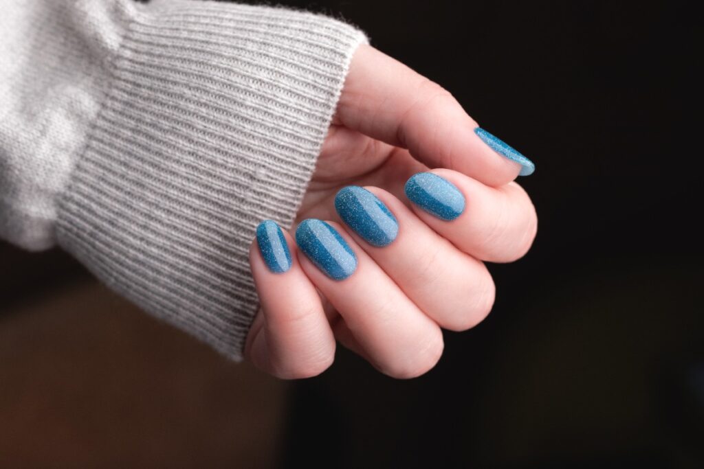 Main avec du vernis à ongles bleu