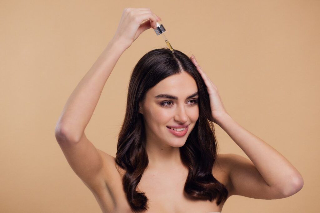 Une femme appliquant de l'huile sur ses cheveux