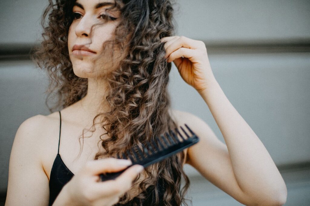 Une femme aux cheveux bouclés tenant une peigne