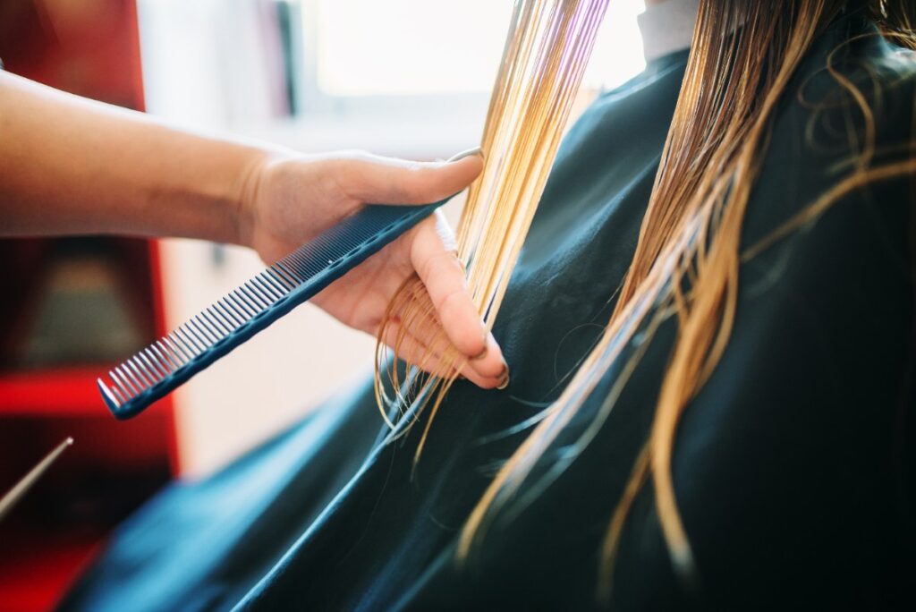 Une femme aux cheveux colorés coupant ses cheveux dans un salon de coiffure