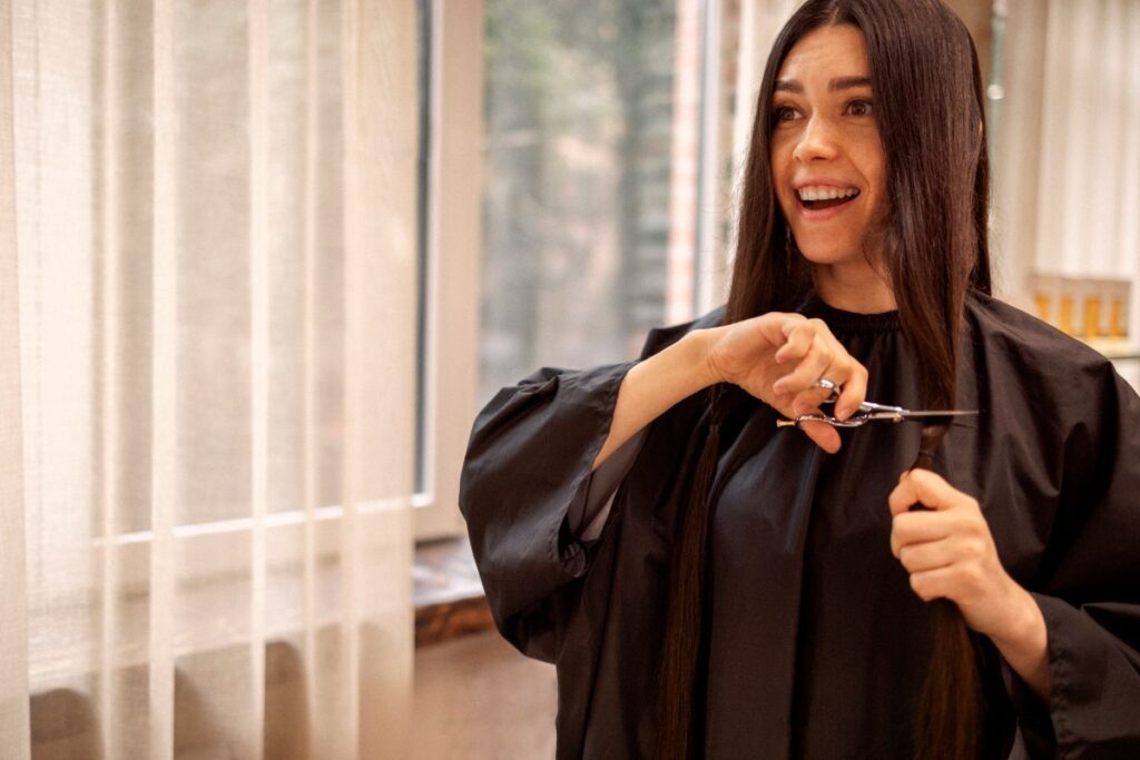 Une femme qui coupe les pointes de ses cheveux