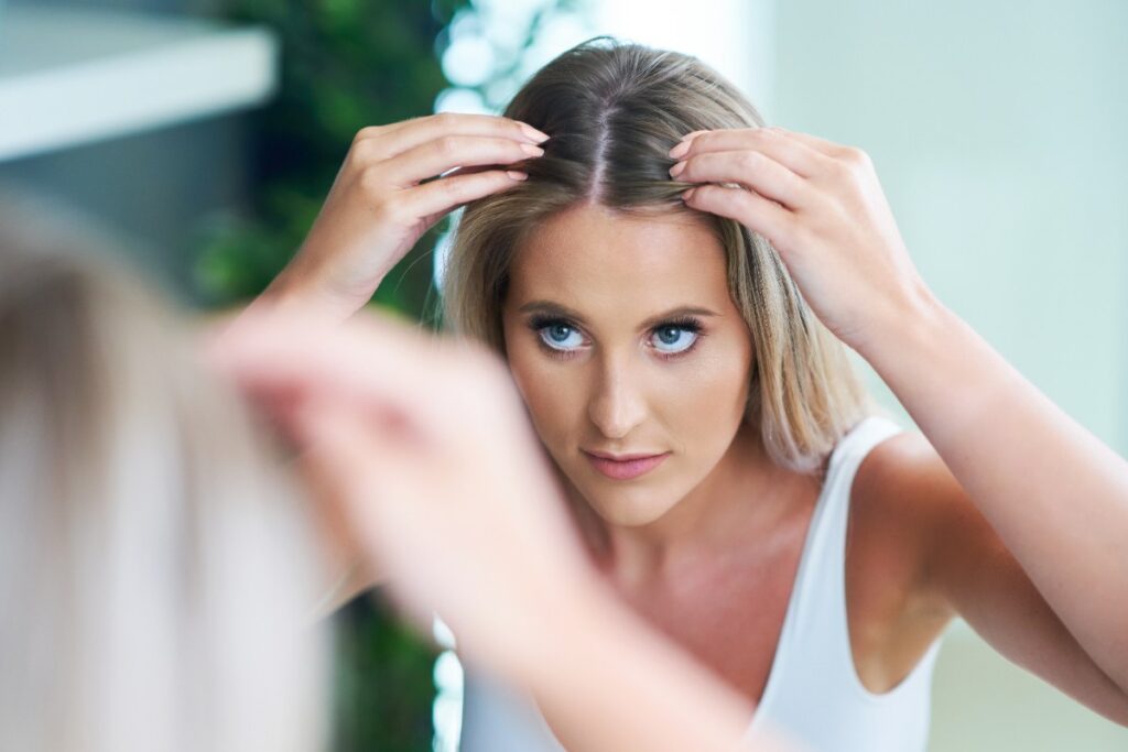 Une femme regardant les cheveux dans le miroir