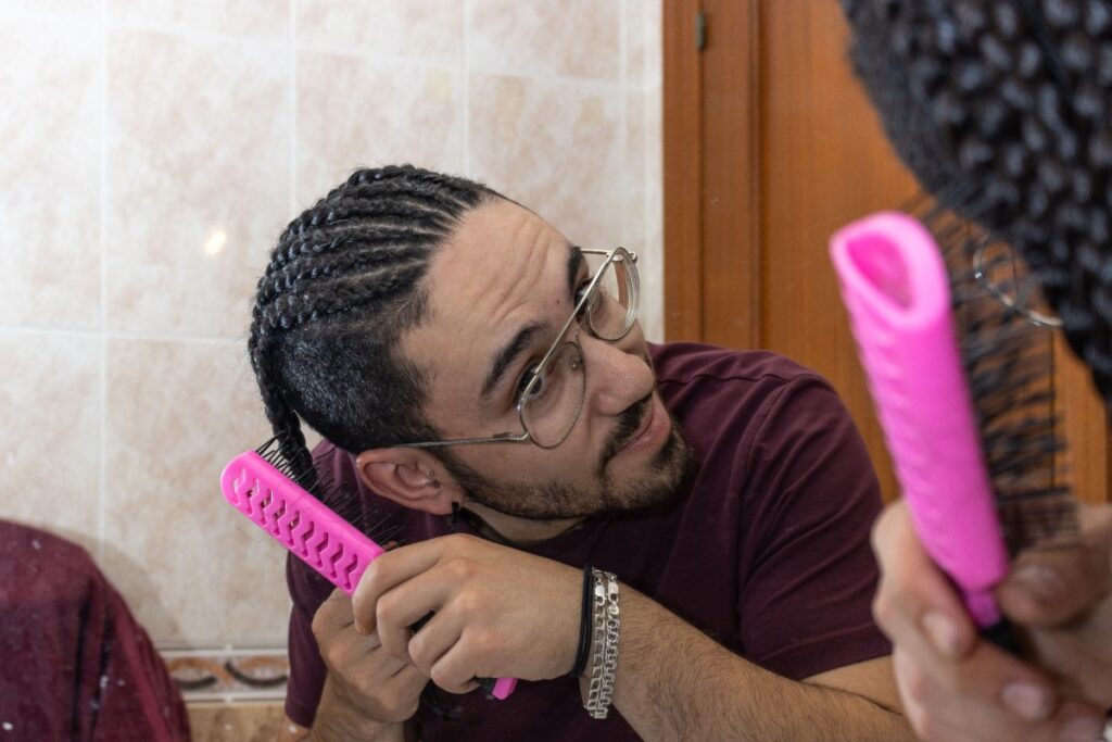 Un homme peignant ses cheveux tressés devant un miroir