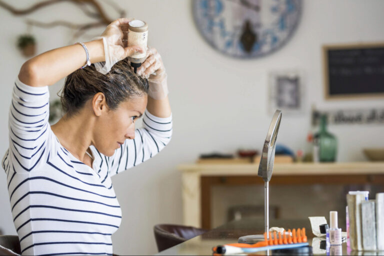 Une femme regarde le mirroir et applique le masque fait maison comme soin de ses cheveux